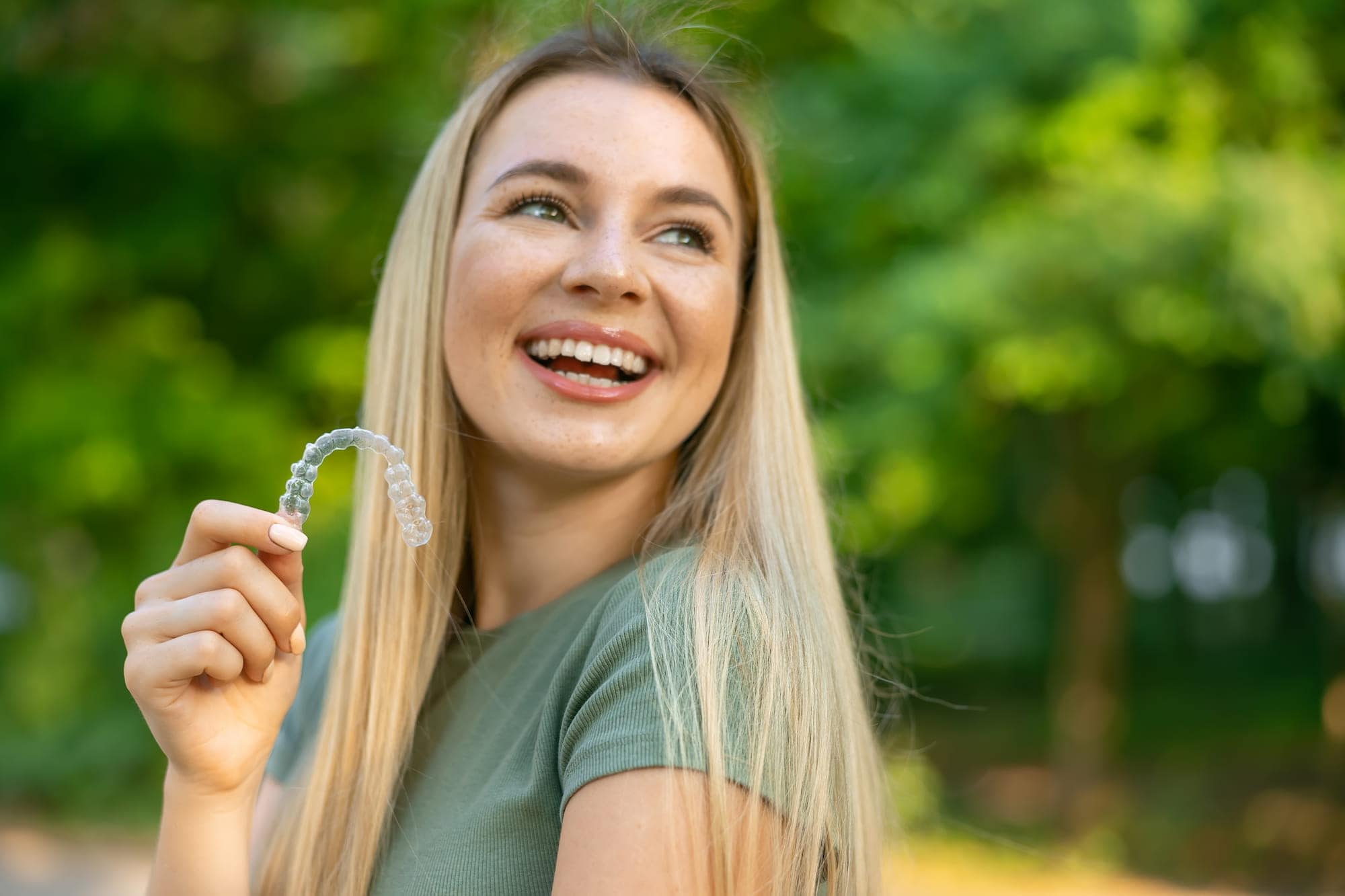 A lady holds up his Invisalign retainer, showing off how inconspicuous it is.
